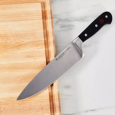 a large knife sitting on top of a wooden cutting board