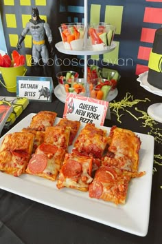 there are many slices of pizza on the plate and in front of them is a batman cake