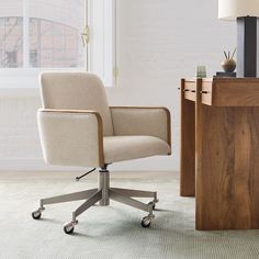 an office chair sitting next to a desk with a lamp on it and a window in the background