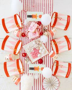 an overhead view of a table with pink and white desserts, candy bars, and paper fans