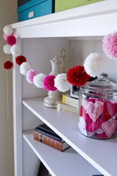 a book shelf filled with lots of pink and white pom - poms on top of it