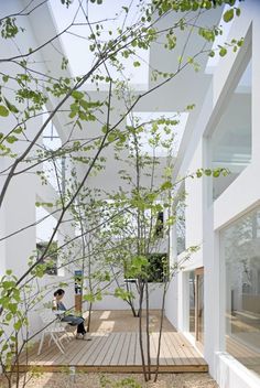 the interior of a modern house with white walls and floors, trees in the foreground