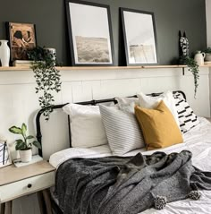 a bed with pillows and blankets on it next to two framed pictures above the headboard