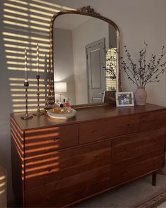 a dresser with a mirror and vase on it