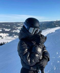 a person standing on top of a snow covered slope wearing a helmet and goggles