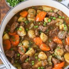 a pot filled with meat and vegetables on top of a wooden table