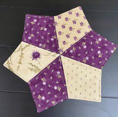 four purple and white patchwork squares on top of each other, with flowers in the center