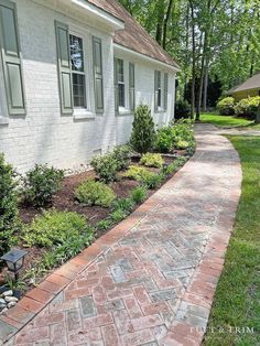 a brick walkway in front of a white house