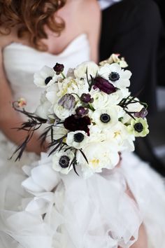 a bride holding a bouquet of white and black flowers