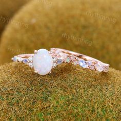 an opal and diamond ring sitting on top of moss