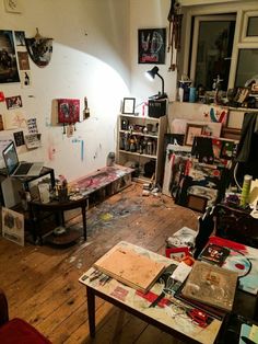 a messy room filled with lots of clutter and art work on the walls,