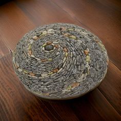 a bowl that is sitting on top of a wooden table with rocks and pebbles in it