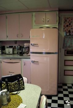 a pink refrigerator freezer sitting inside of a kitchen next to a checkered floor