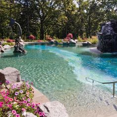 an outdoor swimming pool surrounded by rocks and flowers