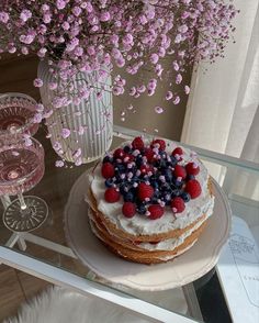 a cake sitting on top of a glass table next to a vase filled with flowers