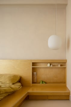 a bed sitting under a white light next to a wooden shelf