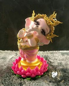 a statue of an elephant with gold and jewels on it's head sitting on top of a pink flower