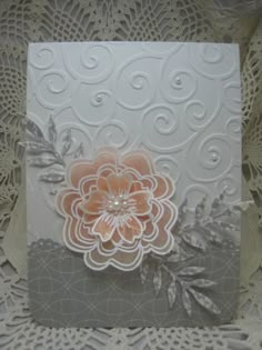 a close up of a greeting card on a lace doily background with an orange flower