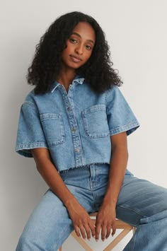 This shirt features a classic collar, button closures, two chest pockets, short sleeves and cropped length with a raw hem. Denim Shirt Outfits, Jean Shirt Outfits, Denim Short Sleeve Shirt, Summer Work Dresses, Denim Shirt Outfit, Cropped Button Up Shirt, Short Sleeve Denim Shirt, Denim Jacket Outfit, Denim Crop Top