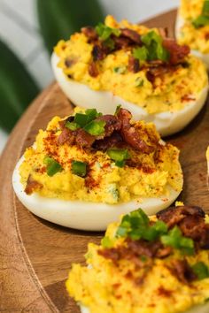 deviled eggs with bacon and chives on a wooden platter, ready to be eaten