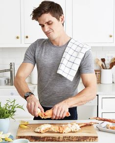 a man cutting up food on top of a wooden cutting board