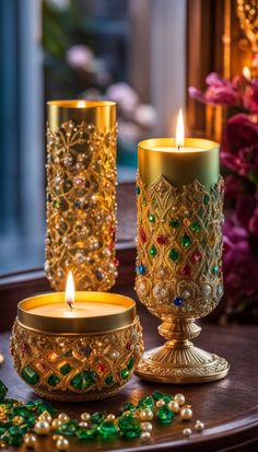 two gold candles sitting on top of a table next to some beads and other decorations