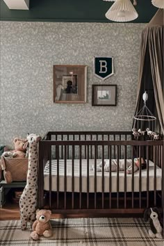 a baby crib with stuffed animals on the floor and in front of it is a wallpapered nursery