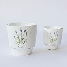 two white cups with blue flowers painted on them