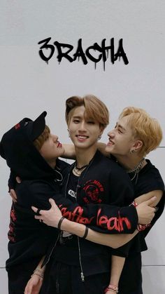 three young men hugging each other in front of a wall with the word'dracula'written on it