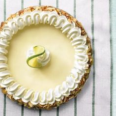 a pie with white frosting on top sitting on a striped table cloth next to a green and white napkin