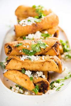 some tacos are on a white plate and garnished with cilantro