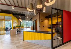 an office with yellow, red and grey walls in the center of it is surrounded by wood flooring