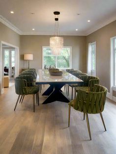 a dining room table with green chairs and a chandelier