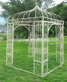 a white metal gazebo sitting on top of a lush green field