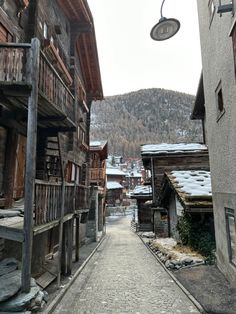 an alley way between two buildings with snow covered mountains in the background