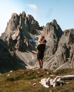 two people standing on the top of a mountain with mountains in the backgroud