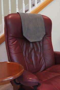 a red leather recliner chair sitting in front of a wooden table and stair case