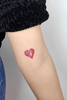 a small heart tattoo on the arm