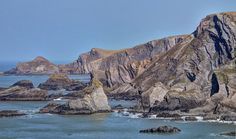 an island with many rocks in the water and some cliffs on one side that look like they have been carved out of rock