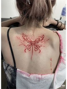 the back of a woman's shoulder with a red butterfly tattoo on her chest