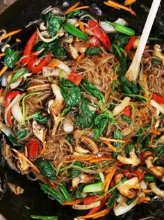 stir fry with vegetables and noodles in a wok on the stove top, ready to be eaten