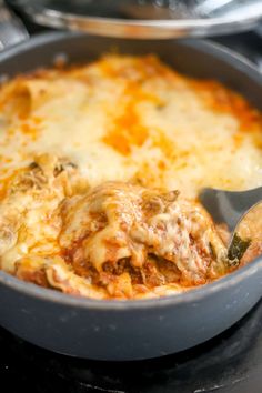 a close up of food in a pan on a stove top with a spatula