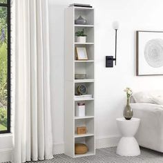 a living room with a white couch and bookcase in front of a large window