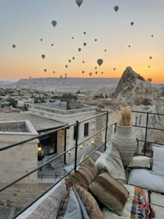 hot air balloons are flying in the sky over a rooftop area with couches and pillows