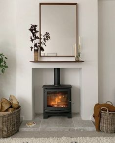 a wood burning stove in a living room next to two baskets and a mirror on the wall