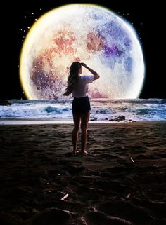 a woman standing on top of a sandy beach next to the ocean under a giant moon