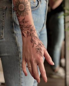 a woman's hand with a sunflower tattoo on it