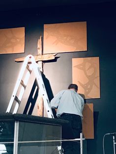 a man standing on a ladder in front of a cross