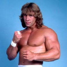 a shirtless man in white trunks holding a tennis racquet and posing for the camera