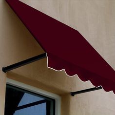 a red awning hanging over a window next to a building with a white door